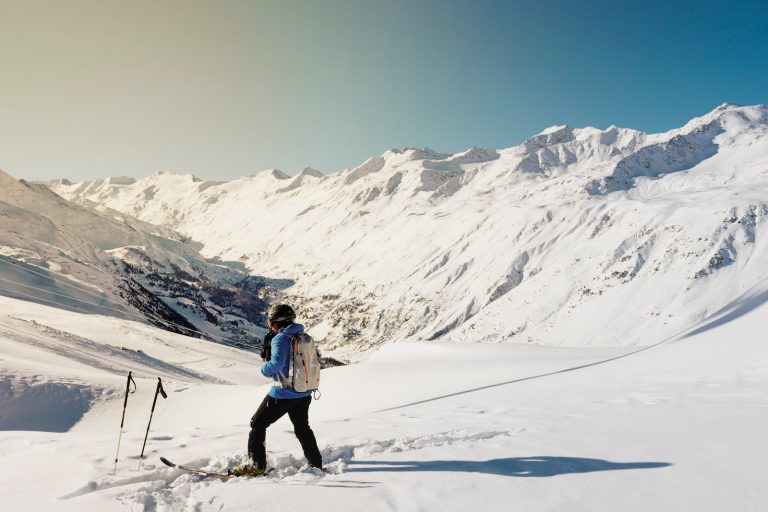 woman in skis standing on snow looking at the mountains