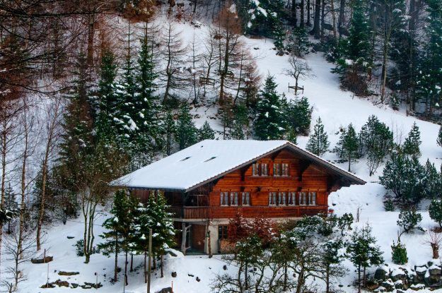 Chalet on a mountain surrounded by trees and snow